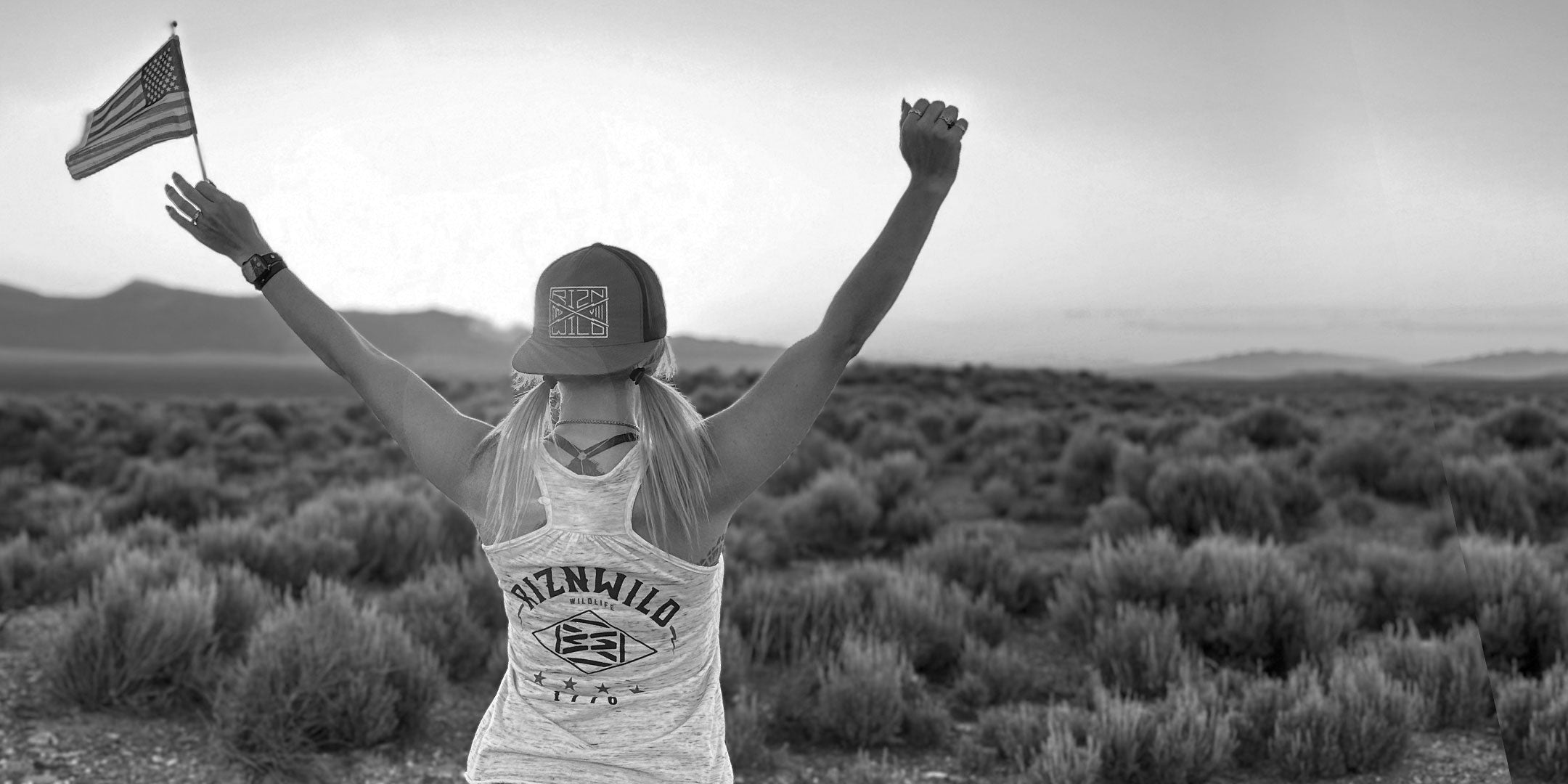 Woman wearing a patriotic RIZNWILD tank raising an American flag outdoors