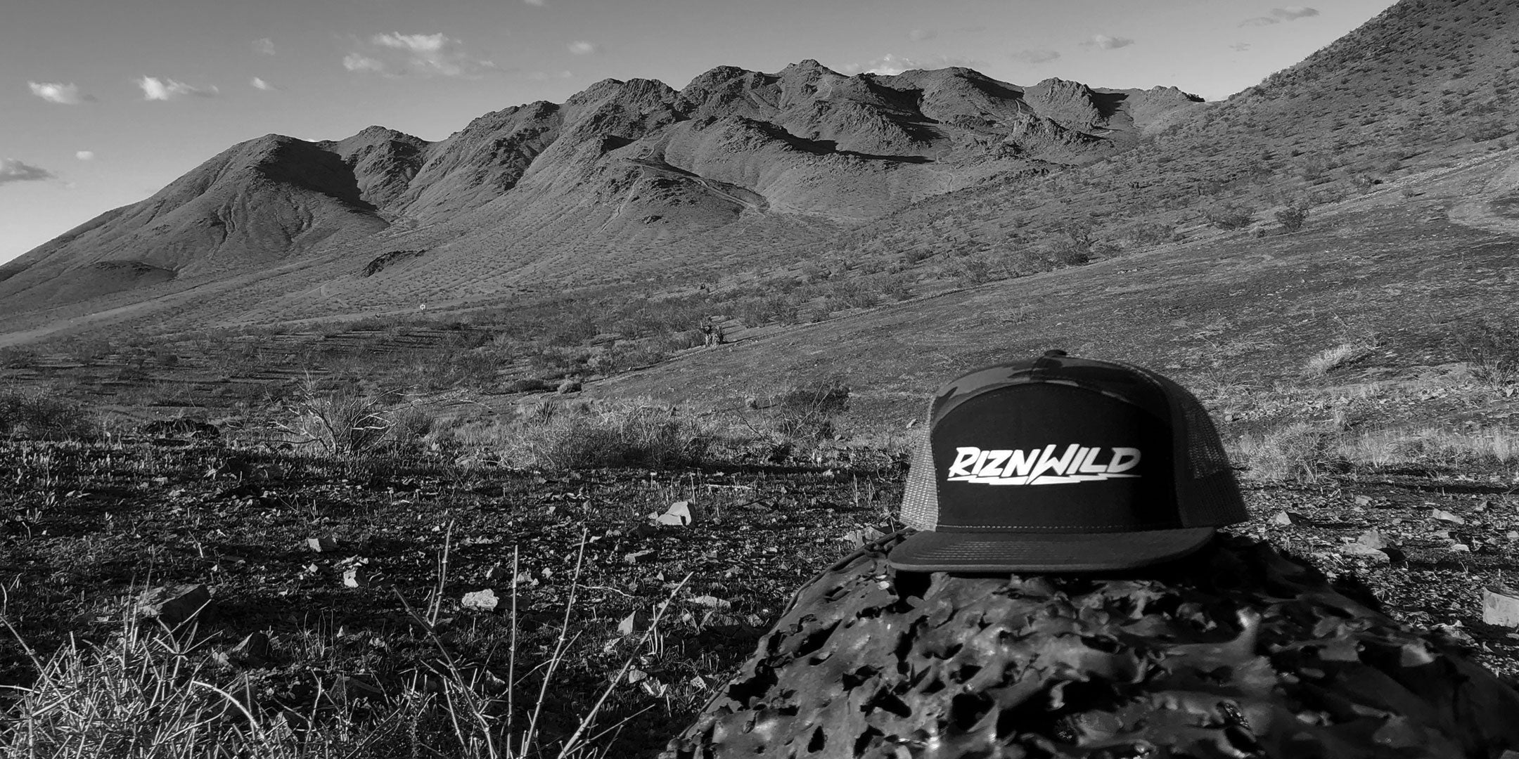 RIZNWILD hat resting on a weathered, shot-up barrel outdoors