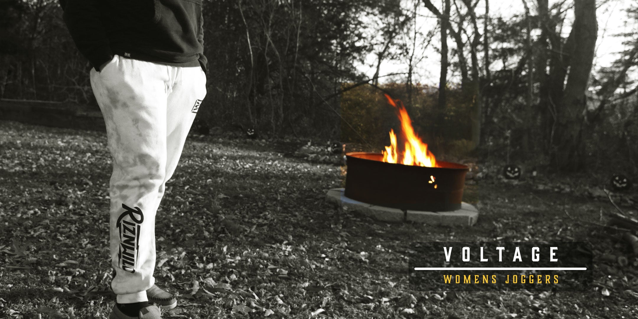 Woman wearing RIZNWILD women’s joggers outdoors near a campfire