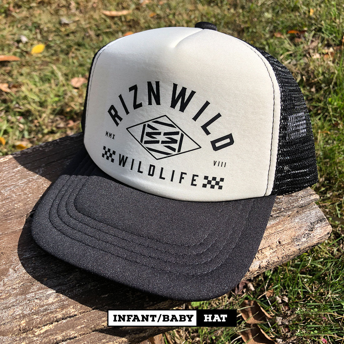 Close-up of RIZNWILD infant hat showing cream front panel and black logo print.