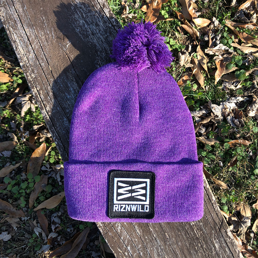 Unisex purple cuffed knit beanie with pom worn in winter