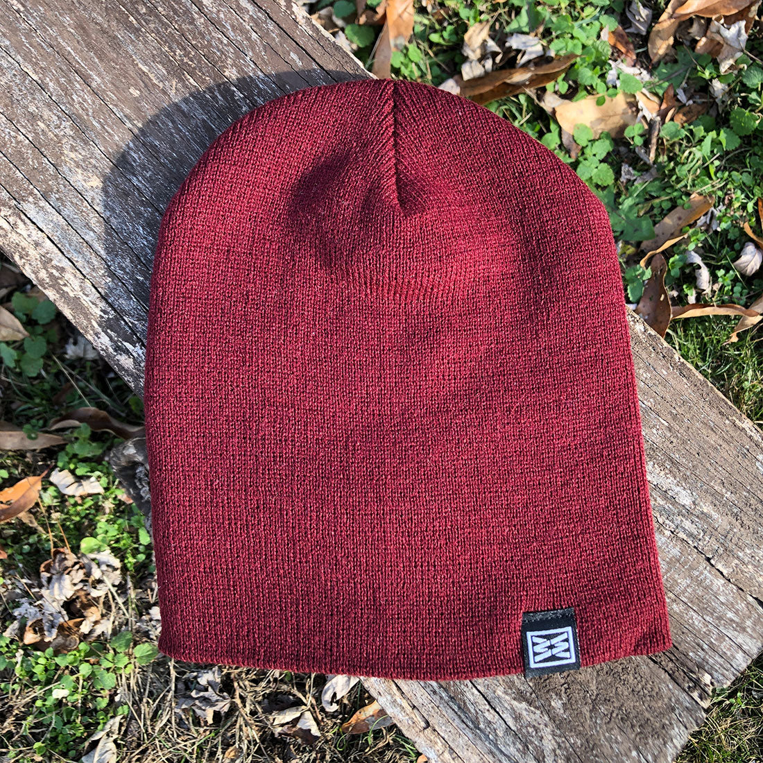 Maroon knit beanie with a RIZNWILD tag on hem.